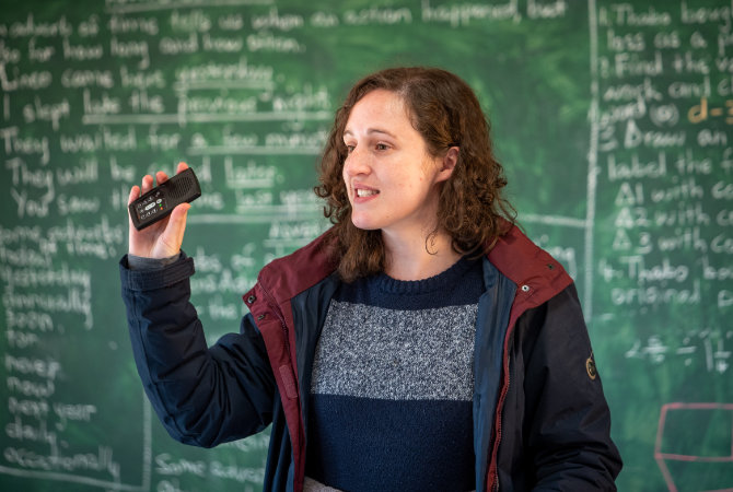 Mitarbeiterin vor einer Schultafel
